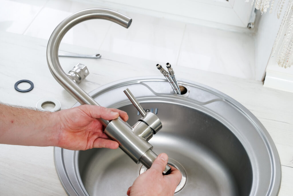 Close-up of plumber hands holding a new faucet for a kitchen sink