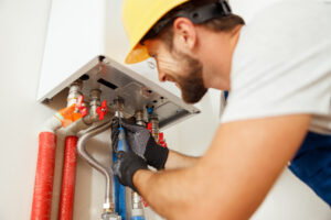 Closeup of plumber using screwdriver while fixing tankless water heater